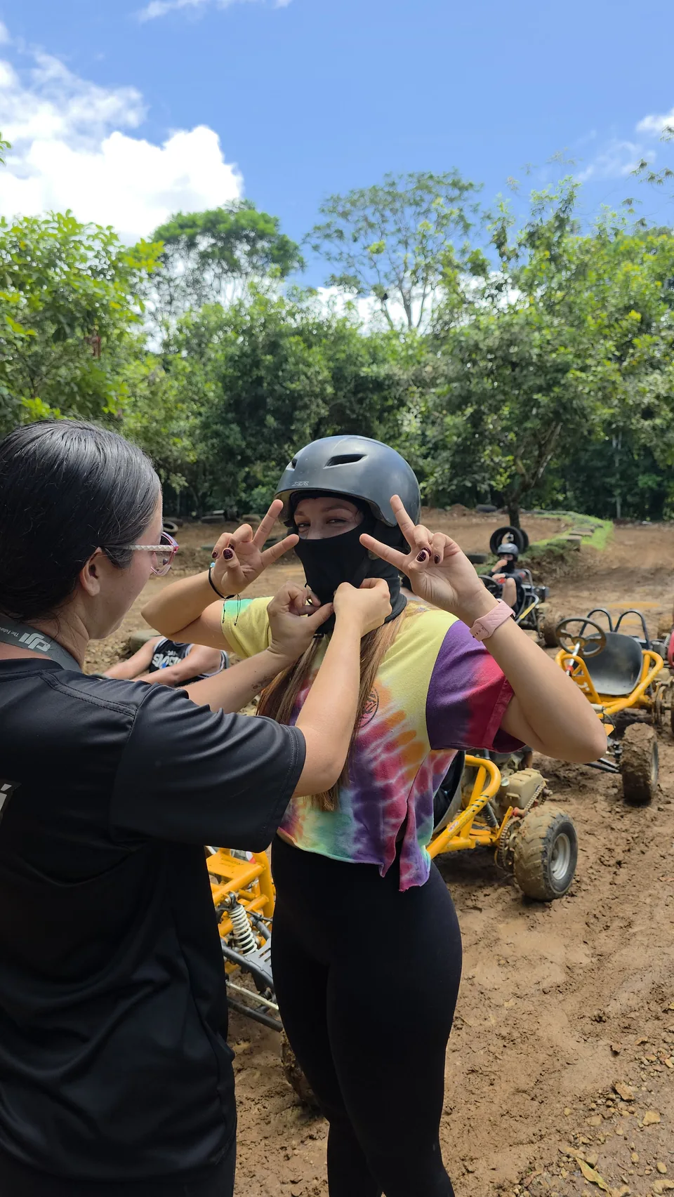Niña con casco de karting hace la señal de paz junto a dos adultos antes de su vuelta en Sarapiquí Race Park