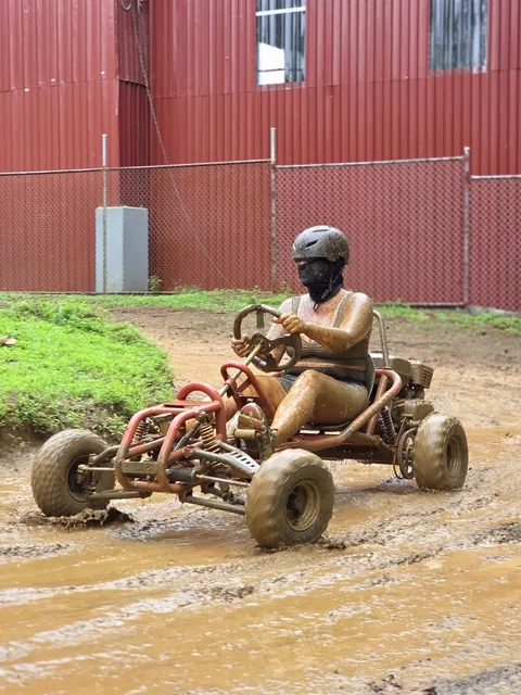 Piloto conduce su go kart junto a la bodega de lámina roja de las instalaciones de Sarapiquí Race Park