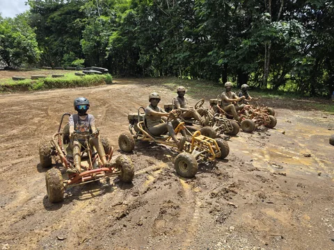 Grupo de cinco pilotos con sus go karts alineados sobre la pista de tierra de Sarapiquí Race Park, rodeados de bosque