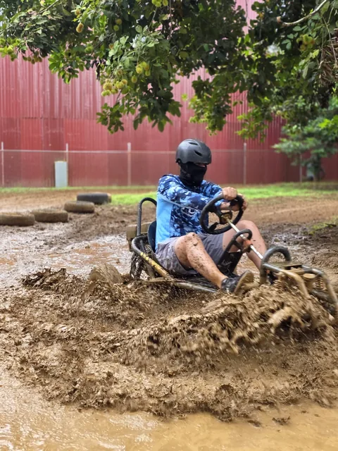 Piloto con camiseta azul cruza un gran charco de lodo generando una fuerte salpicadura sobre la pista