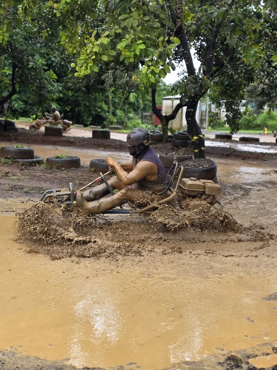 Piloto cruza un charco de lodo a toda velocidad en su go kart, generando una fuerte salpicadura