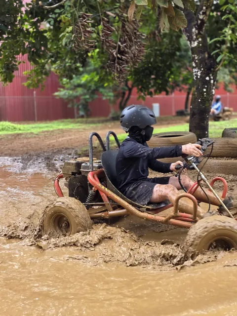 Piloto atraviesa un pozo de lodo profundo con su go kart, con llantas apiladas de fondo delimitando la pista