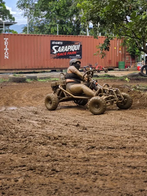 Piloto cubierto de lodo conduce su go kart frente a las instalaciones de Sarapiquí Race Park